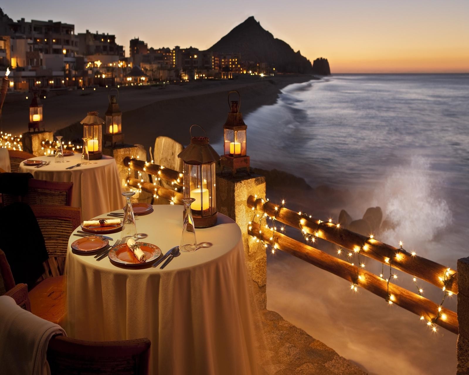 Mesas montadas en una playa con velas y linternas (playa, cena, montaña, pueblo, ola)