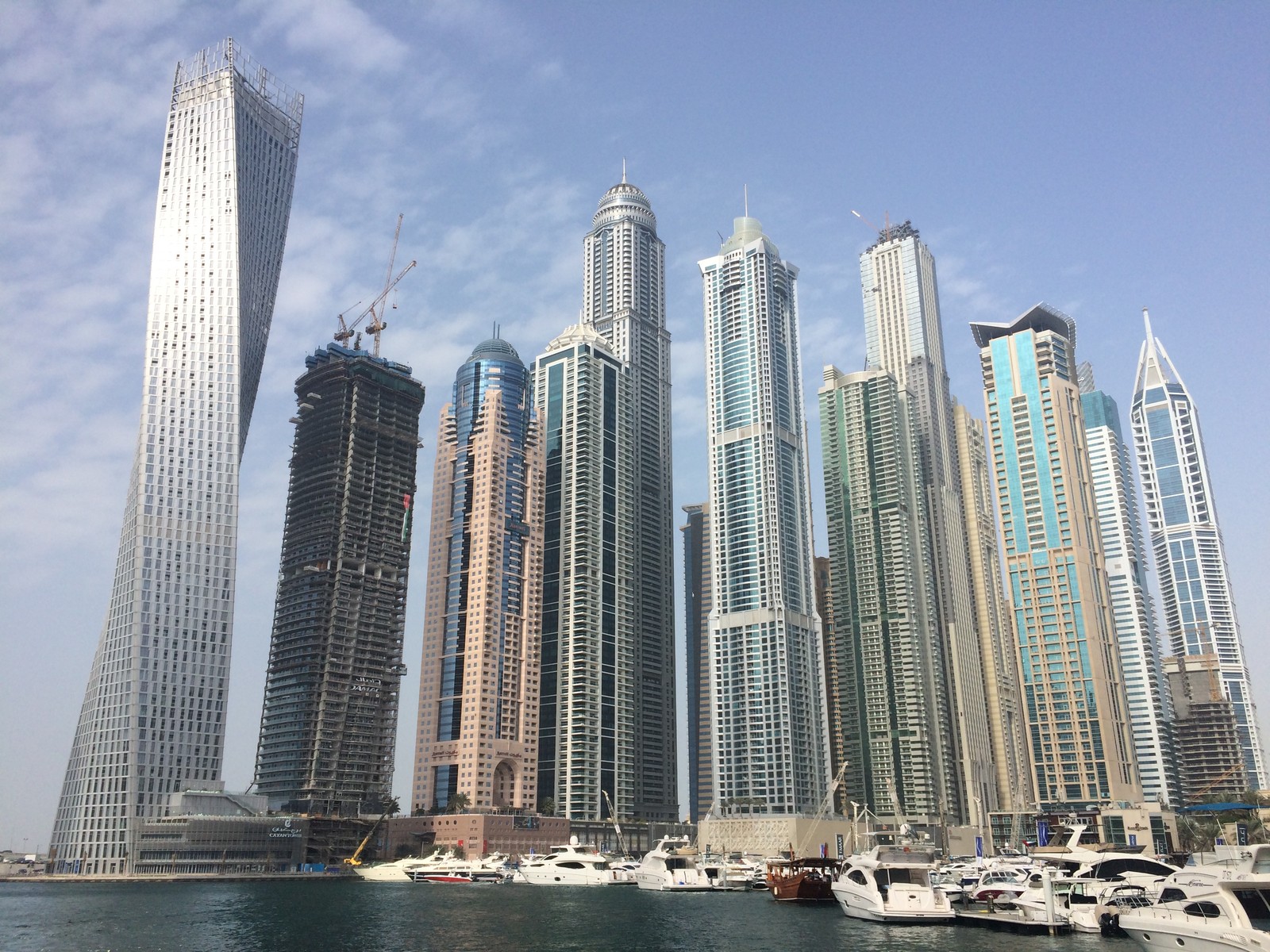 Barcos estão ancorados na água em frente a uma grande cidade (dubai, miami, arranha céus, bloco de torre, cidade)