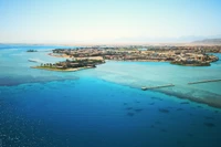 Une vue aérienne époustouflante de la côte de Louxor, avec des eaux bleues vibrantes, des complexes luxuriants et un archipel serein, parfait pour des vacances et l'exploration des voies navigables.