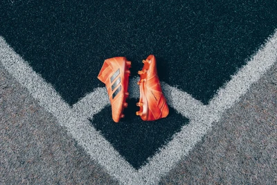 Botas de fútbol Adidas rojas sobre asfalto con sombra