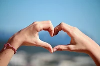 Hands Forming a Heart Shape Against a Bokeh Background