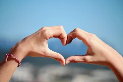 Hands Forming a Heart Shape Against a Bokeh Background