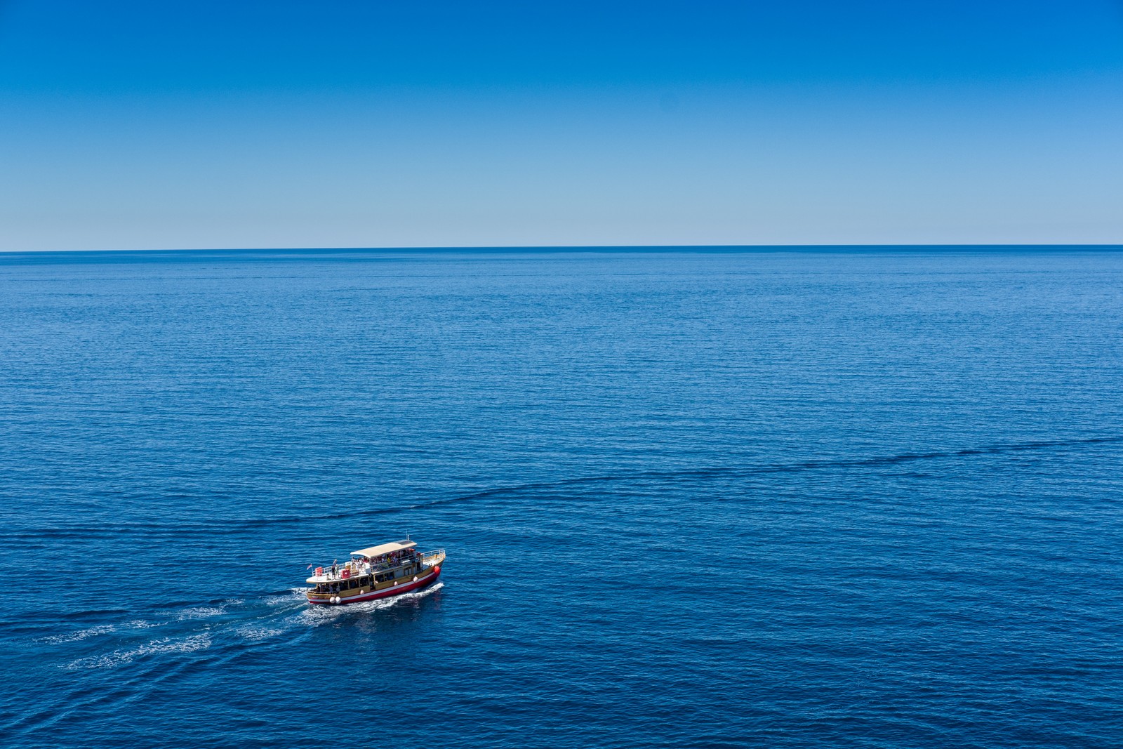 Barco arafed en medio del océano con un cielo azul claro (mar, cuerpo de agua, azul, horizonte, transporte acuático)