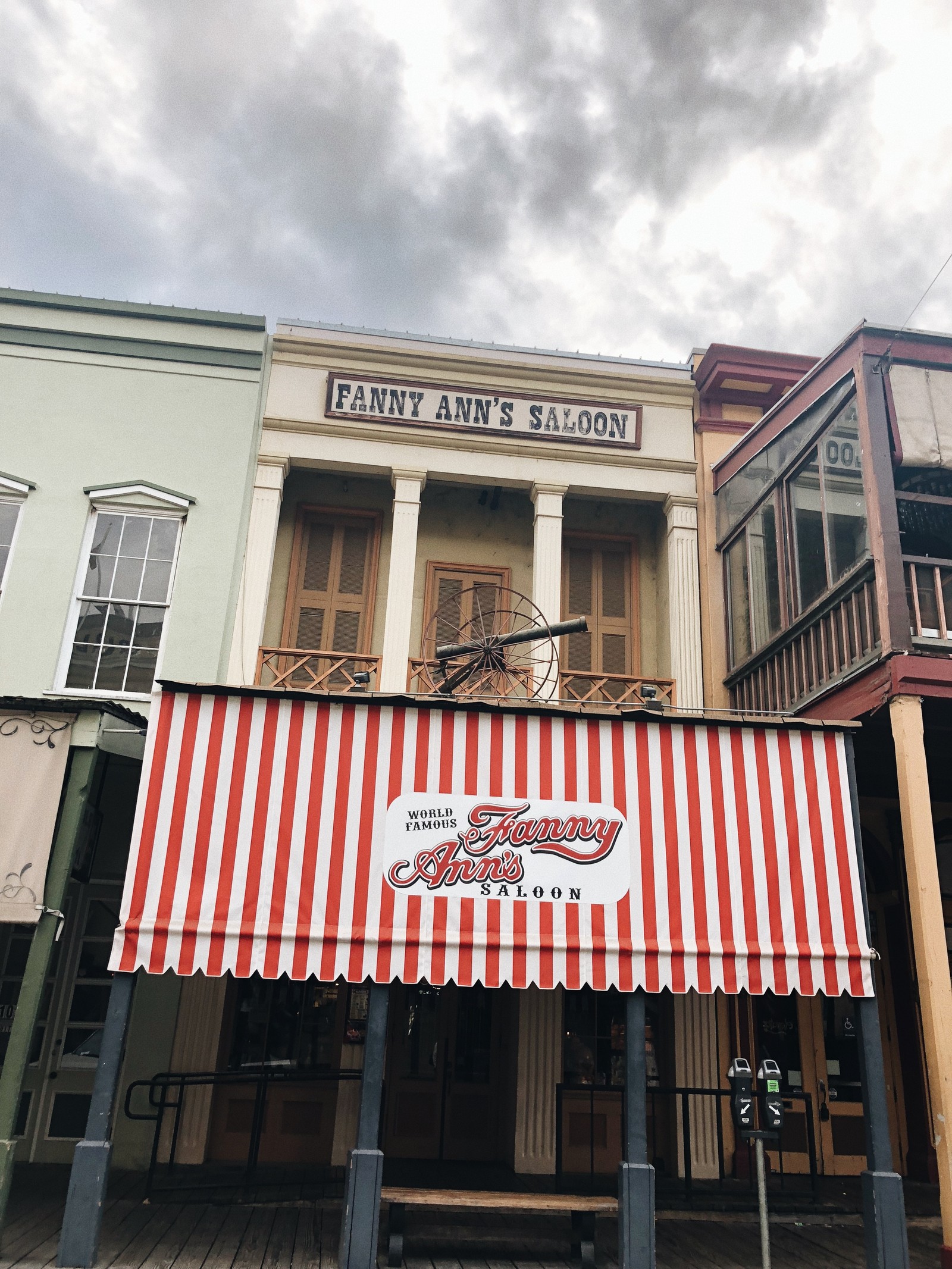 There is a red and white awning on the front of a building (landmark, real estate, facade, iron, signage)