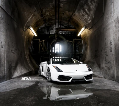 White Lamborghini Gallardo Spyder parked in a dimly lit, industrial tunnel with reflections on the wet floor.