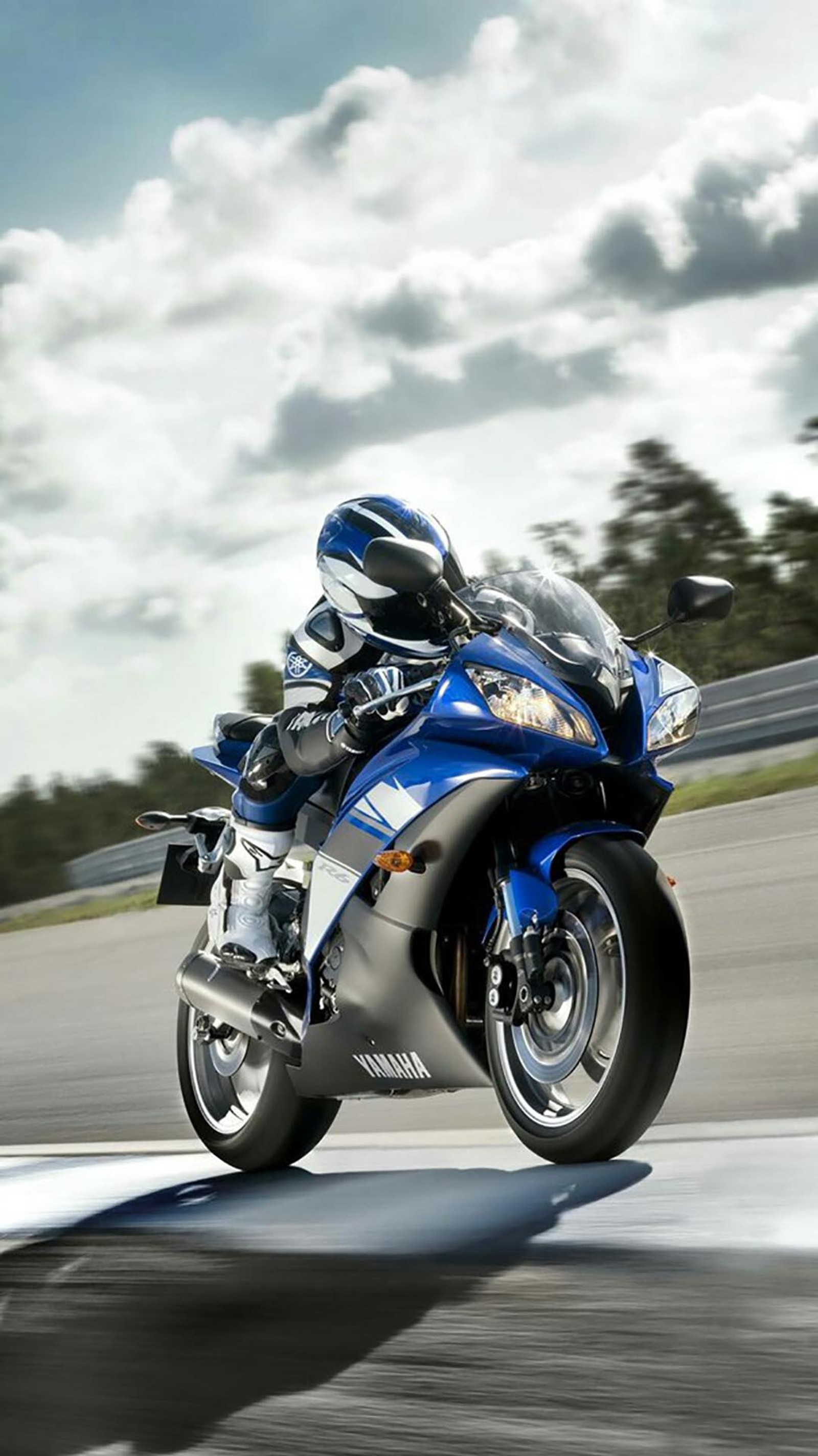 There is a man riding a motorcycle on a track on a cloudy day (moto, motors)