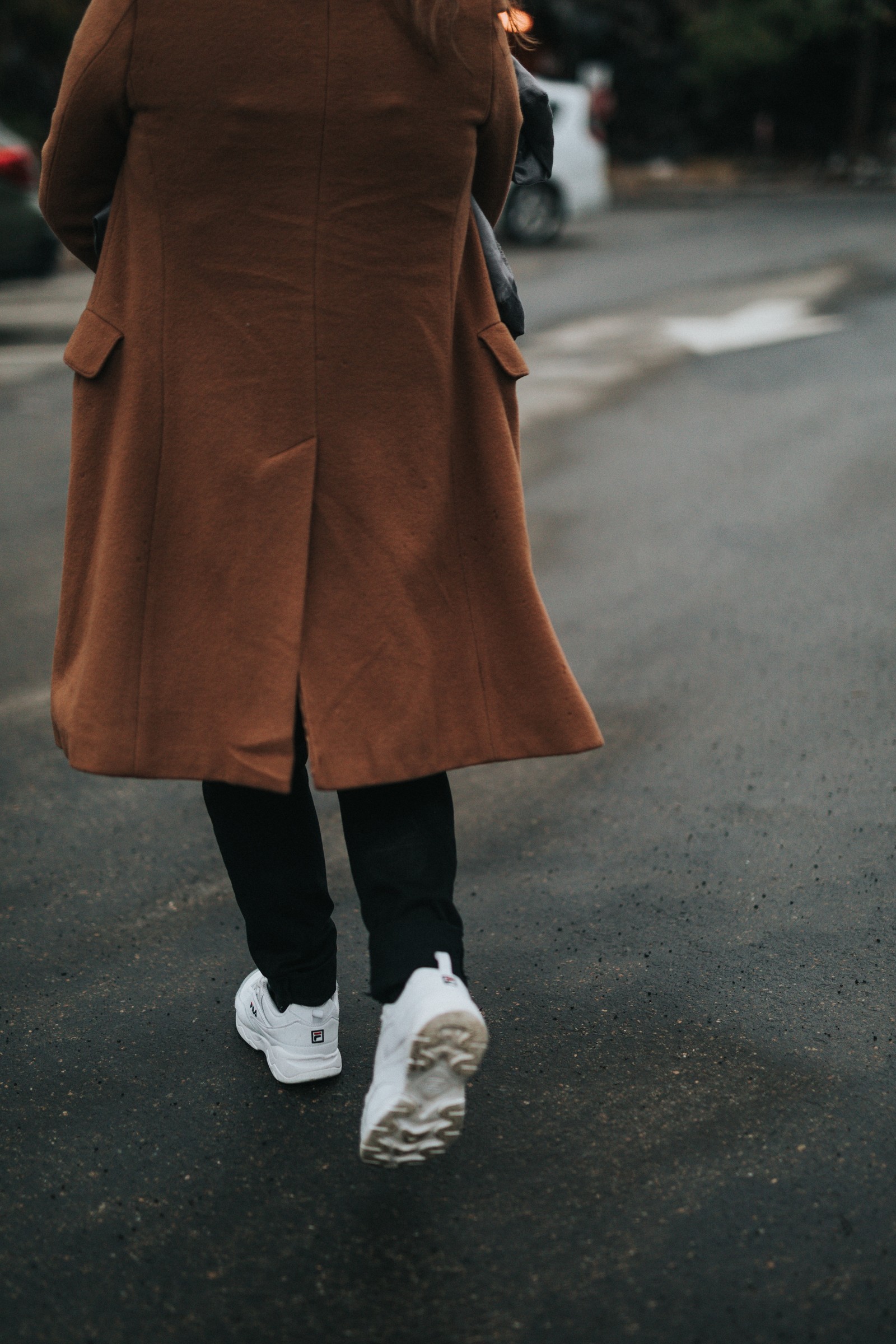 Il y a une femme qui marche dans la rue avec un parapluie. (vêtements, chaussures, mode de rue, jambe humaine, marron)