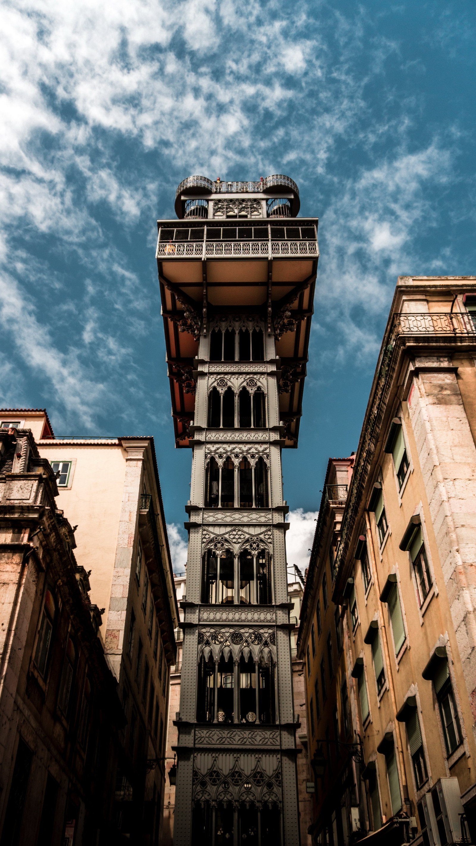 There is a tall tower with a clock on it in the middle of a city (cloud, building, window, house, tower block)