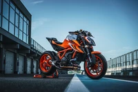 2022 KTM 1290 Super Duke R EVO in auffälligem Orange, auf einer Rennstrecke mit klarem blauen Himmel präsentiert.