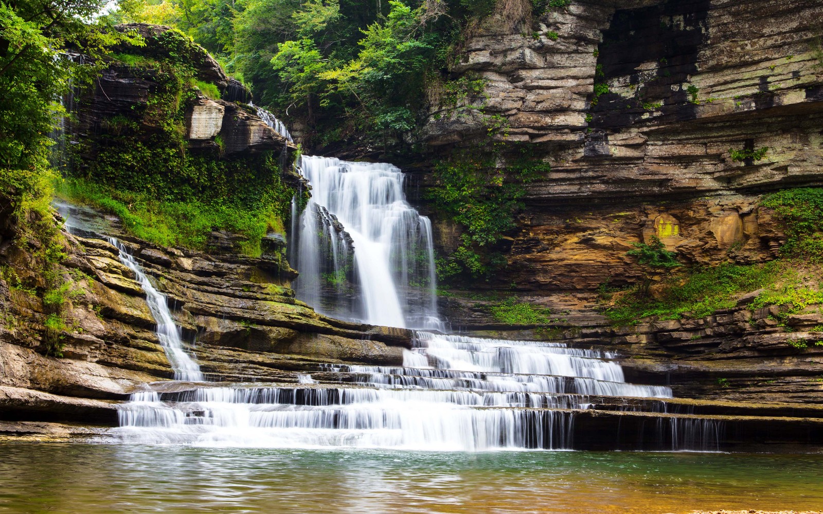 Ein wasserfall inmitten einer felsigen schlucht, umgeben von bäumen (wasserfall, wasserlauf, naturschutzgebiet, gewässer, wasserressourcen)