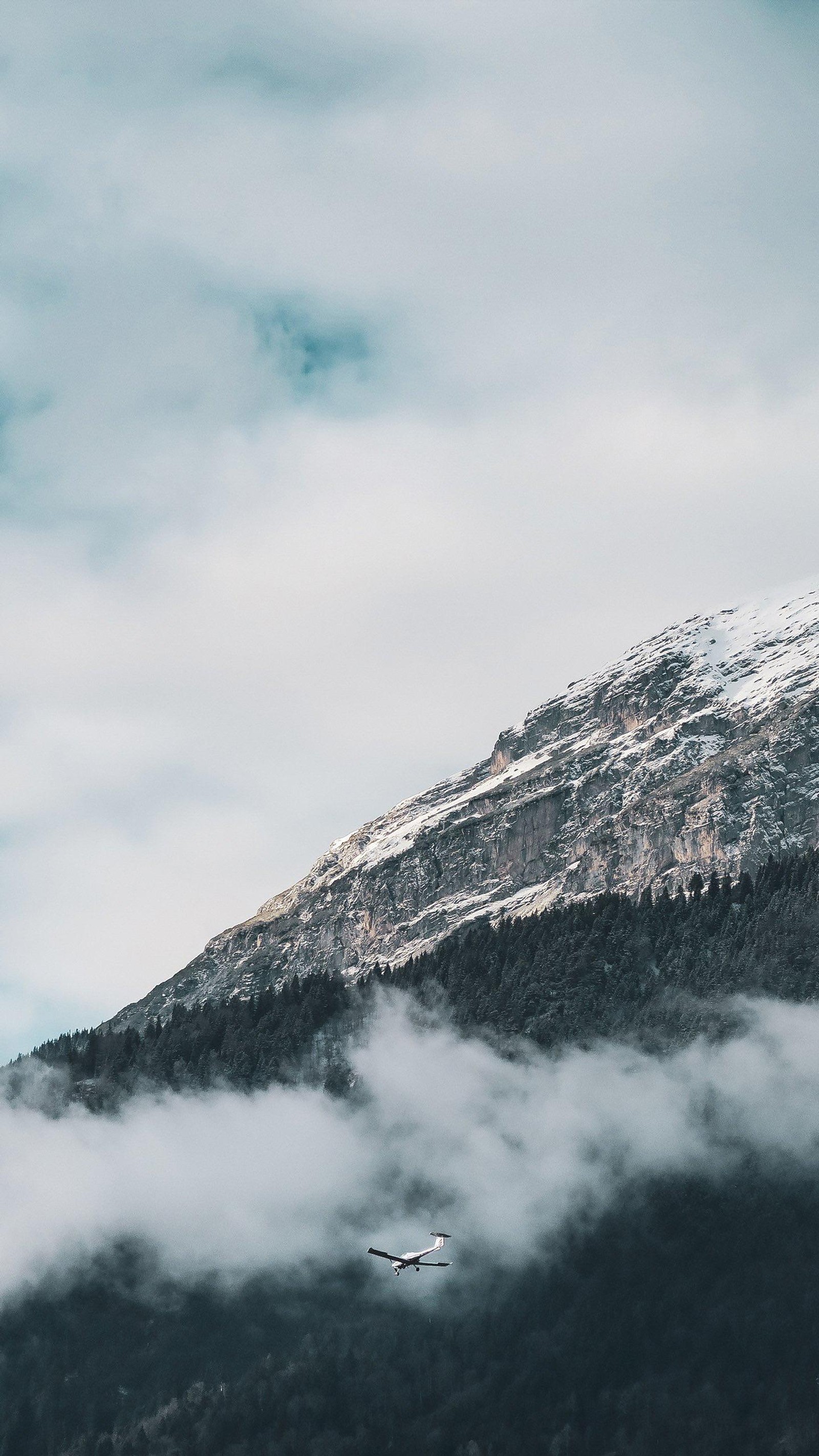 There is a plane flying over a mountain with a cloud (cloud, atmosphere, mountain, natural landscape, slope)