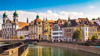 Encantadora cidade à beira do lago com arquitetura histórica e reflexos vibrantes ao longo do canal, emoldurada pelos Alpes suíços.