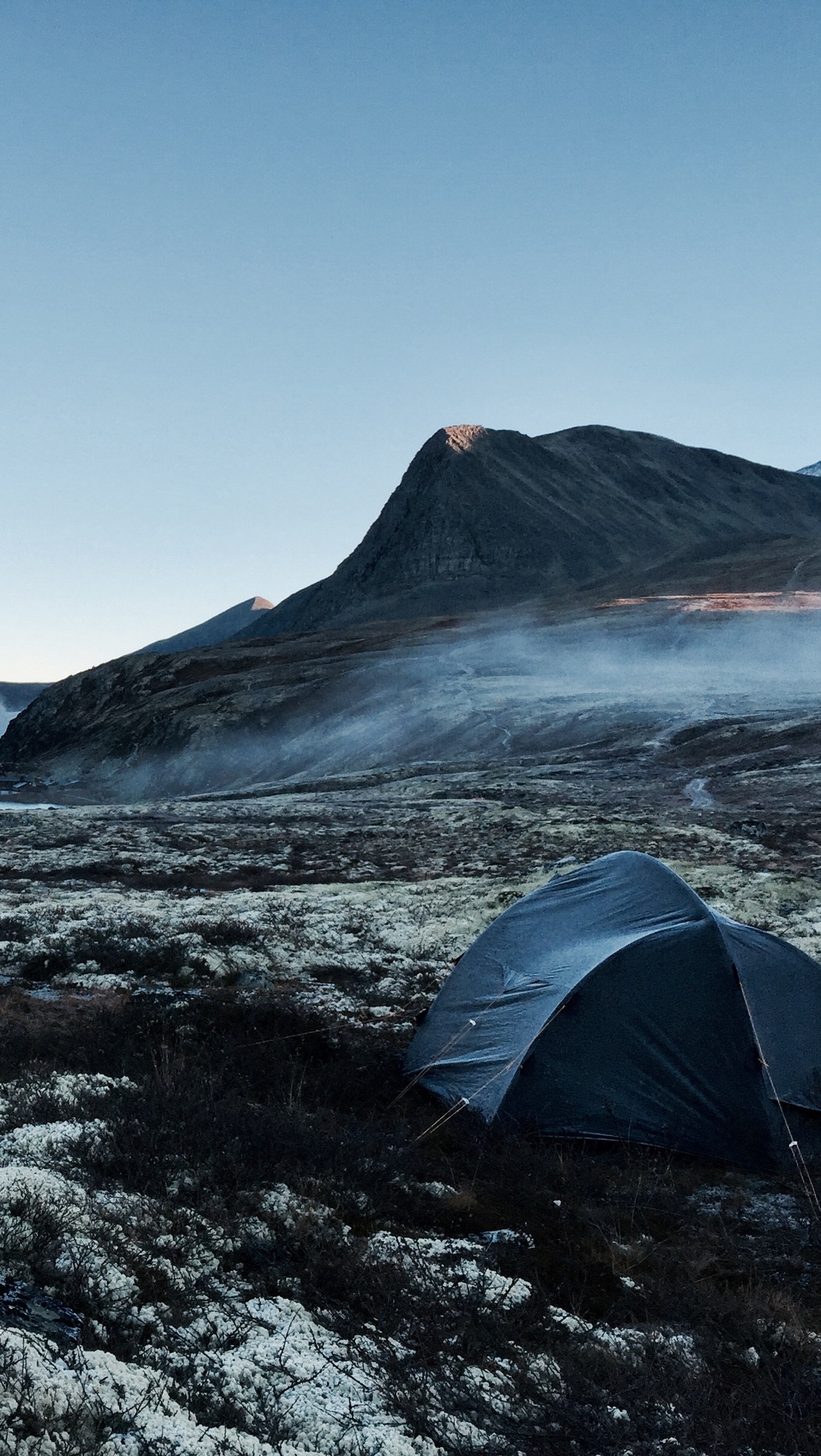 There is a tent pitched up in the middle of a field (bluebird, life, morning, mountains, nature)