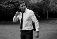 Tom Hardy em um terno sob medida, adotando uma pose confiante em um cenário em preto e branco.