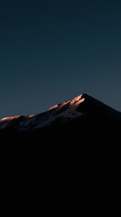 Illuminated Mountain Peak Against a Darkening Sky