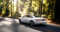 Sleek Lincoln sedan cruising through a serene forested road.