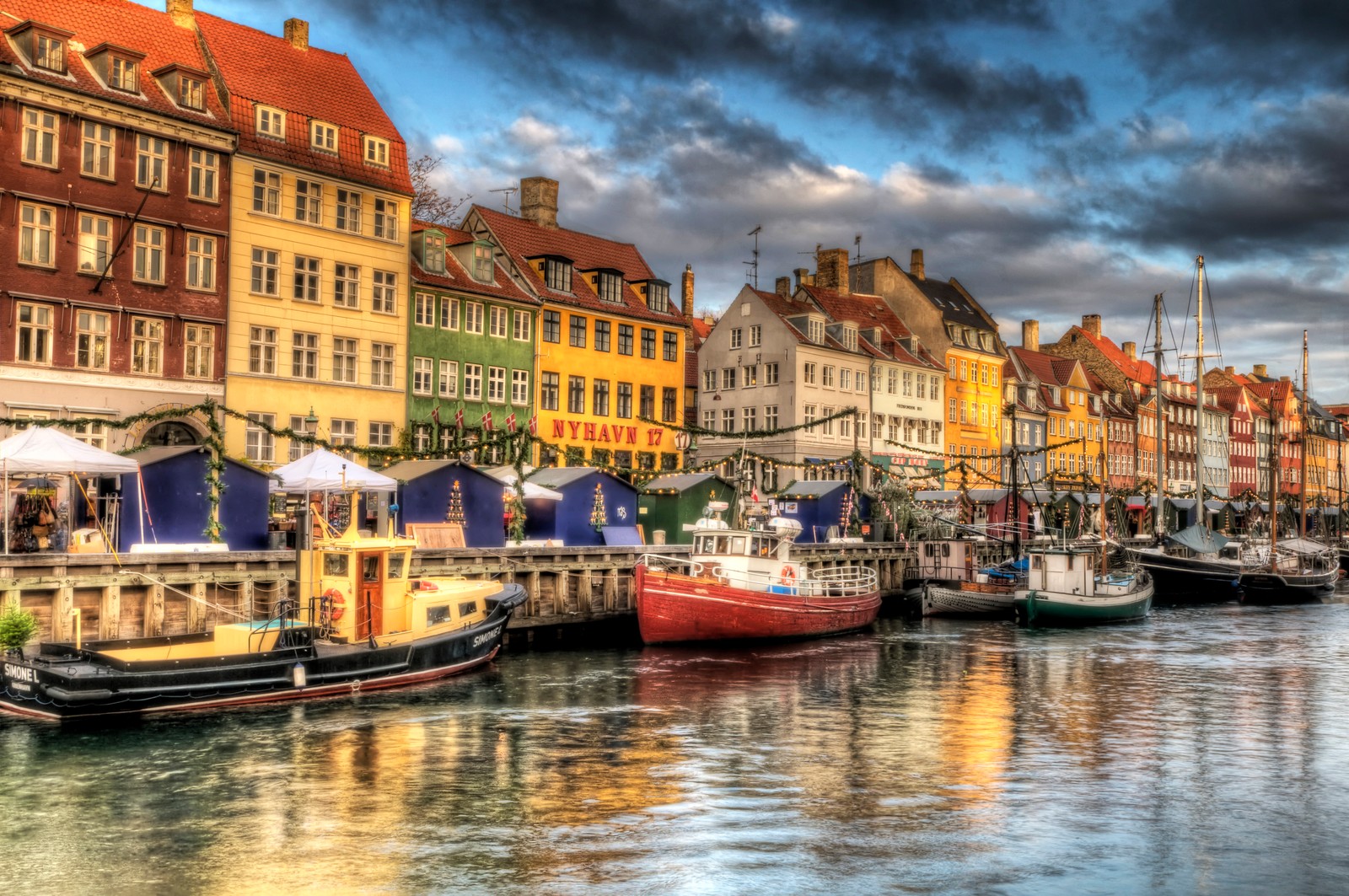 Boats are docked in a harbor with buildings in the background (copenhagen, water transportation, body of water, waterway, reflection)