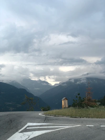 Kurvenreiche Straße durch eine bergige Landschaft unter bewölkten Himmel