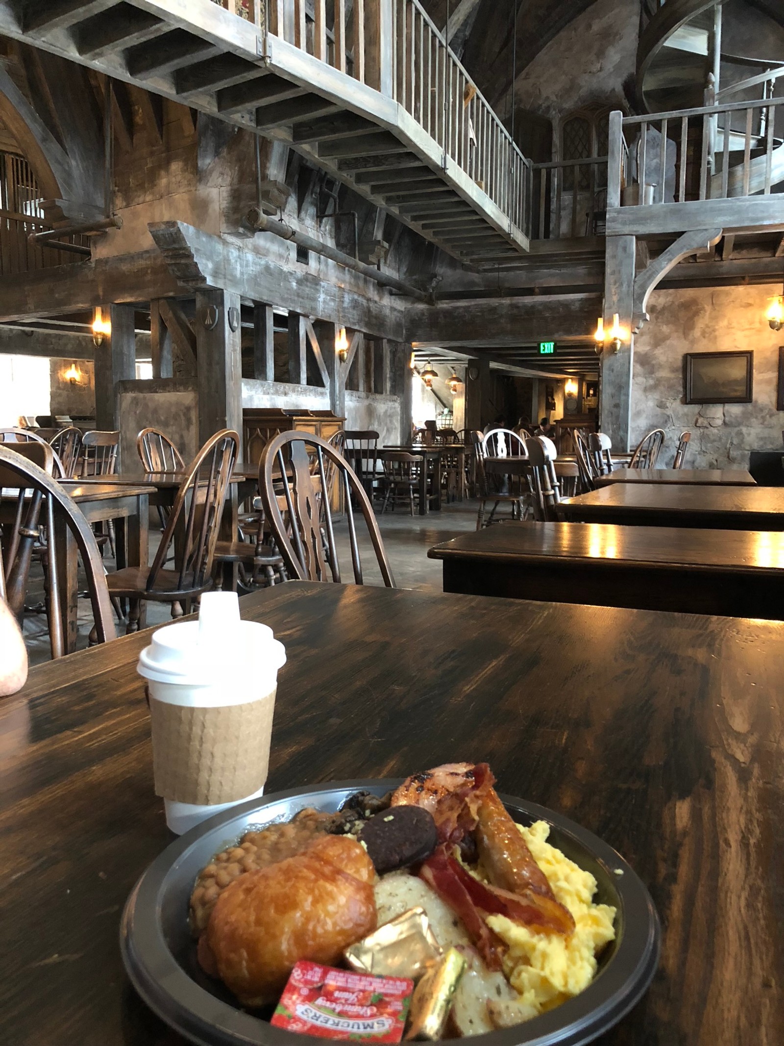 Il y a une assiette de nourriture sur une table avec une tasse de café (poudlard, hogwarts, brunch, bois, cuisine)