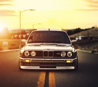 Vintage grauer BMW M3 auf einer offenen Straße bei Sonnenuntergang