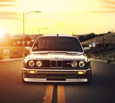 BMW M3 grise vintage sur une route ouverte au coucher du soleil