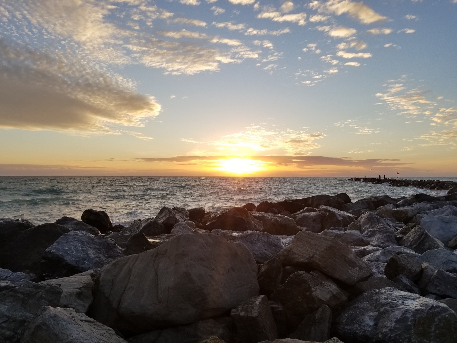 Vue panoramique d'un coucher de soleil sur l'océan avec des rochers et de l'eau (plage, paysage, océan, photos, rochers)