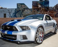 Eleganter silberner Shelby Mustang mit auffälligen blauen Akzenten vor urbanem Wandgemälde