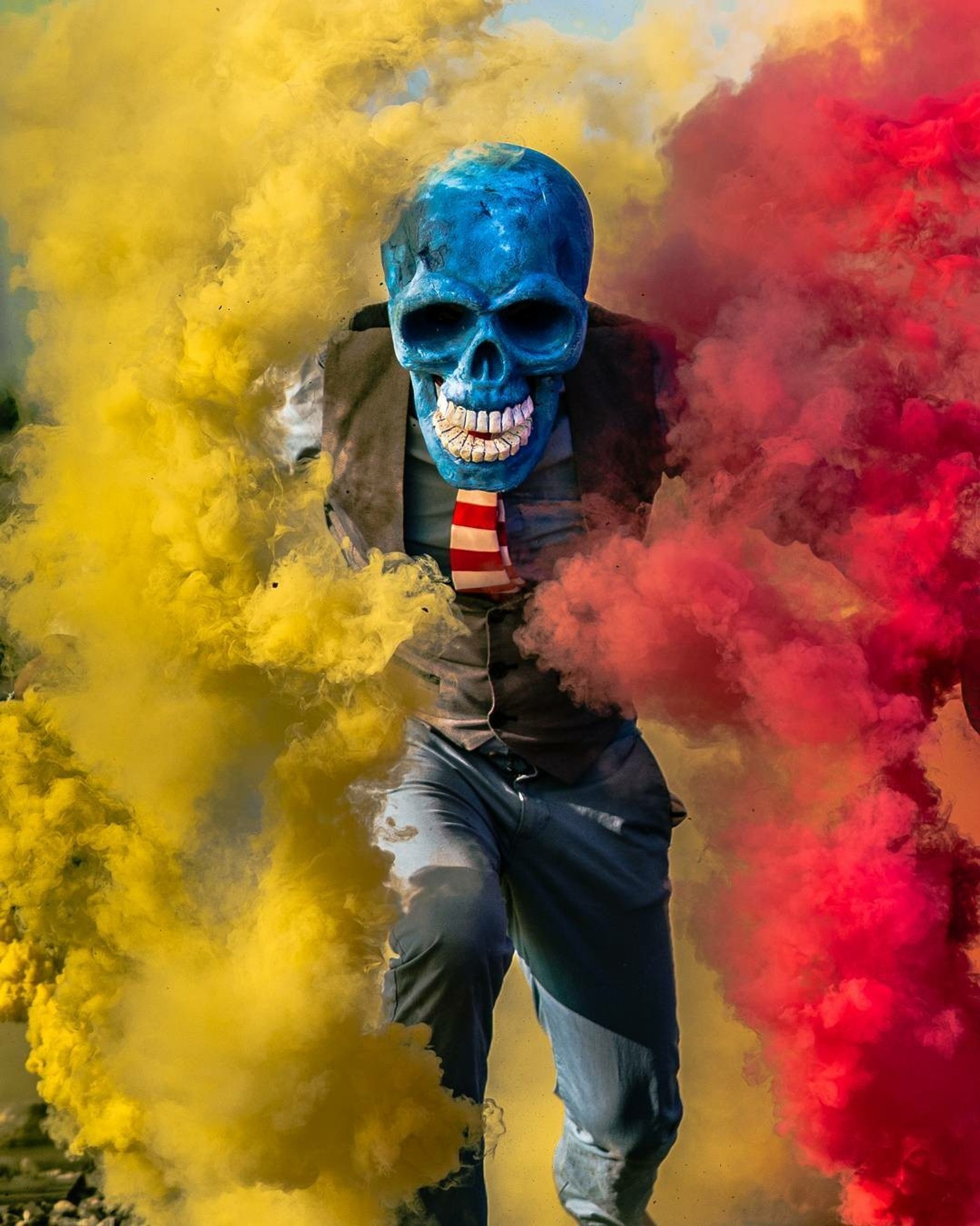 Un homme avec un visage bleu et une cravate courant à travers la fumée (couleurs, génial, mort, crâne, fumée)