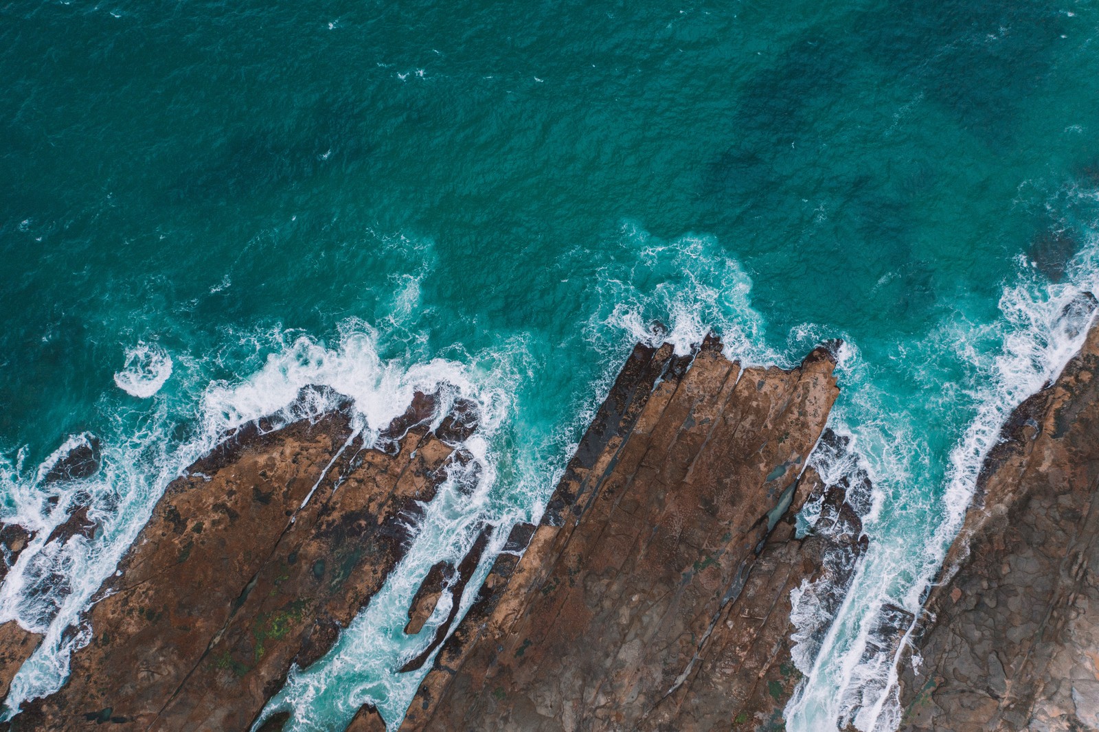 Aerial view of waves crashing on rocks in the ocean (shore, piracy, ocean, blue, turquoise)