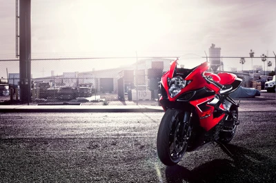 Stunning red Suzuki GSX-R motorcycle parked in an urban setting with a sunlit backdrop.