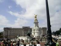 Buckingham Palace und das Victoria Memorial auf einem belebten Stadtplatz, gefüllt mit Touristen an einem sonnigen Sommertag.