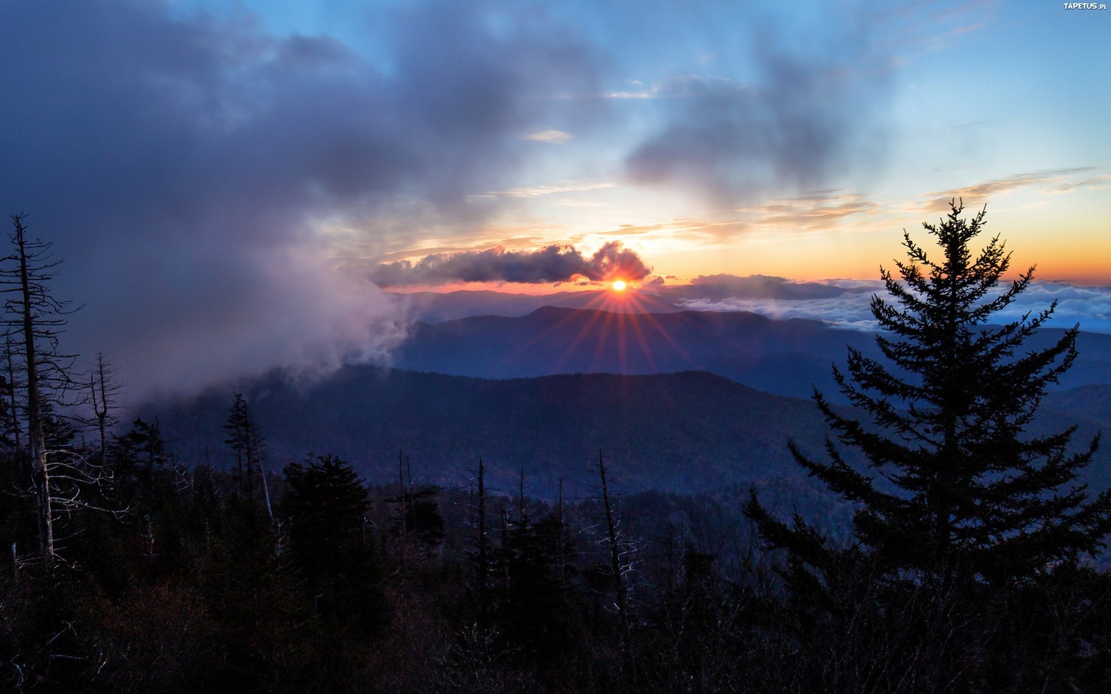 A view of the sun setting over the mountains from a mountaintop (landscape, nature, cloud, wilderness, sunrise)