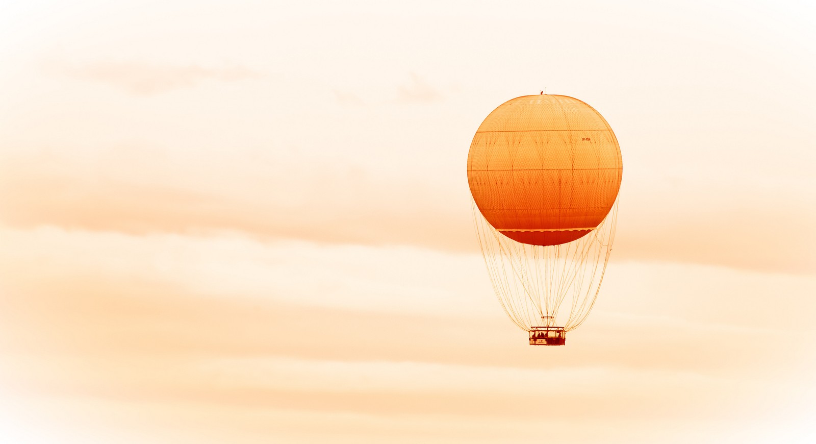 Un grand ballon orange vole dans le ciel avec un fond de ciel (montgolfière, ballon, sable)