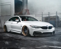 BMW M4 blanche élégante avec des roues dorées dans un cadre urbain