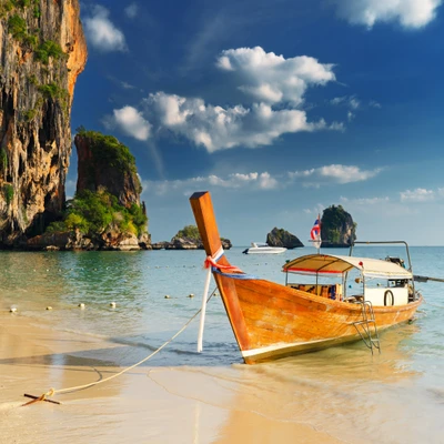 Paraíso tropical: praia serena com um barco de madeira e falésias cênicas