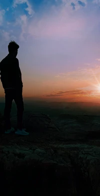 Menino contemplativo olhando para um vibrante pôr do sol na natureza