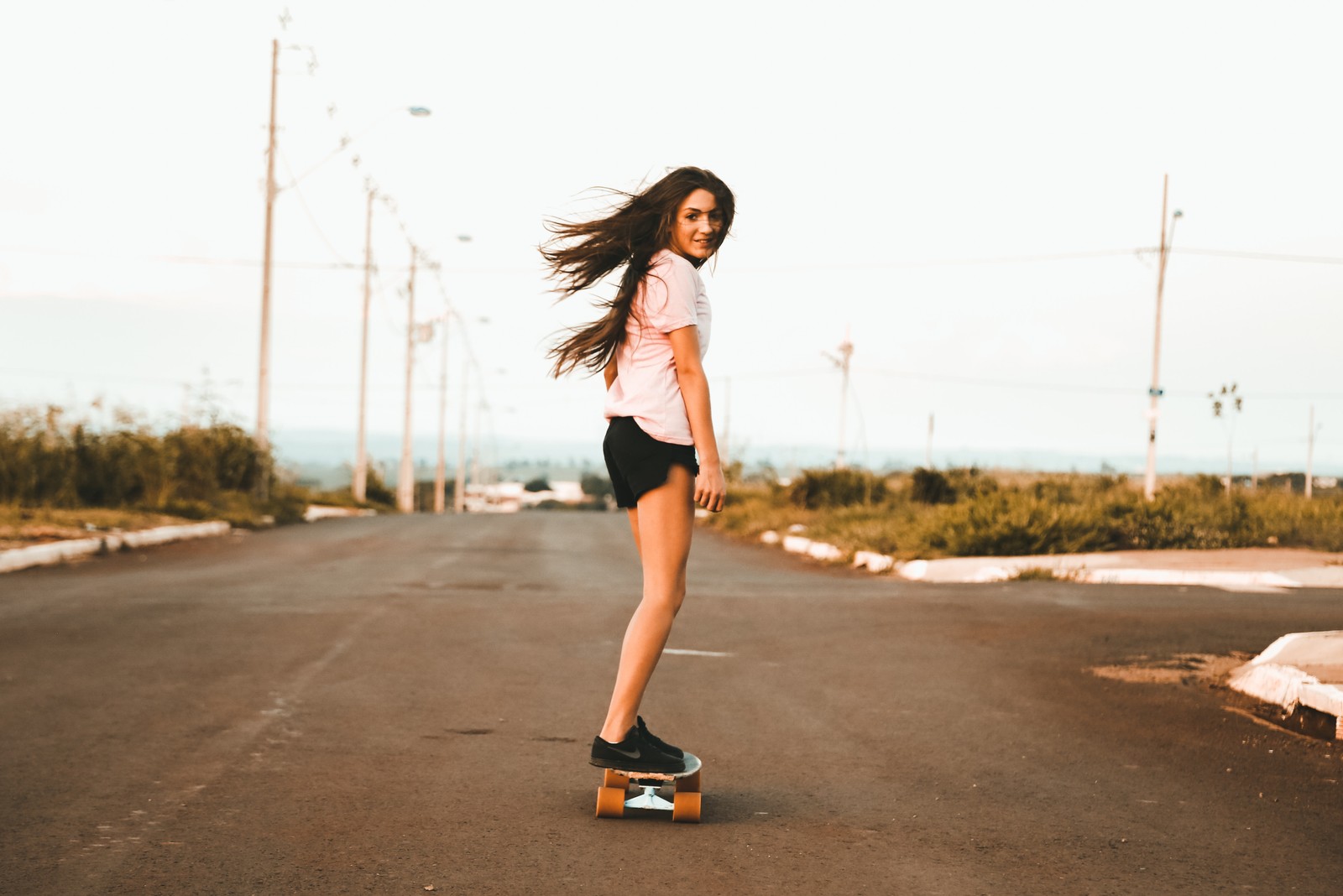 Arafed woman riding a skateboard down a street with her hair blowing in the wind (skateboard, skateboarding, longboard, longboarding, footwear)