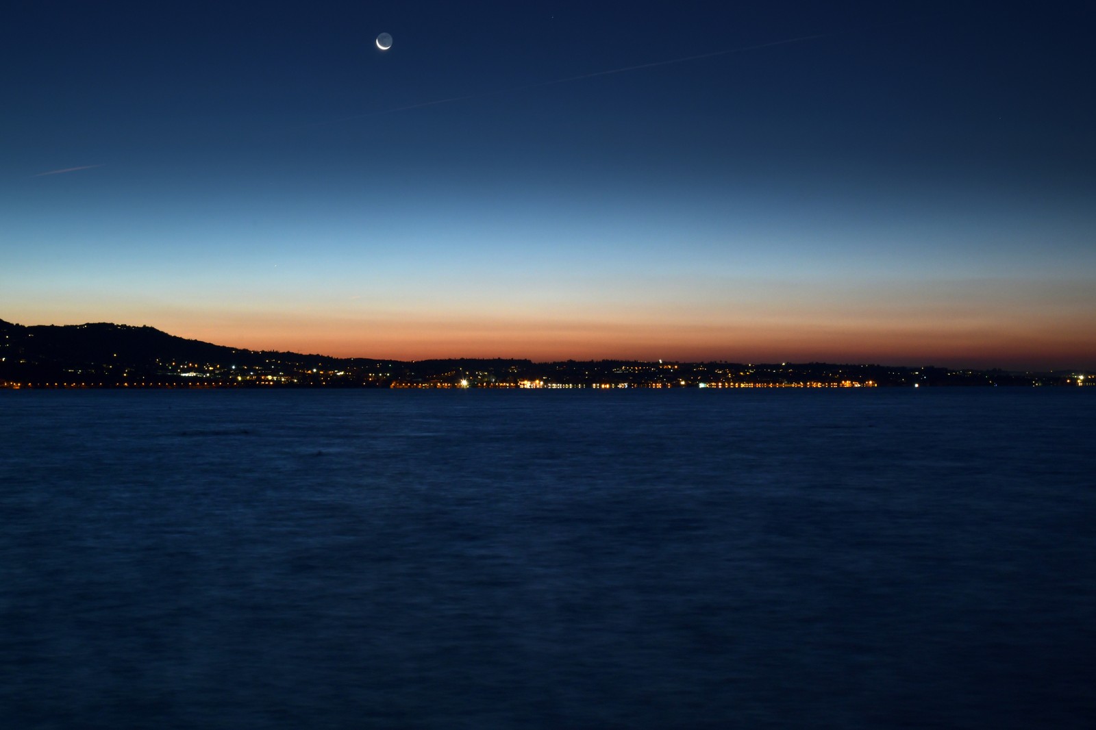 Vista árabe de uma cidade à noite com uma lua no céu (azul, horizonte, água, noite, mar)