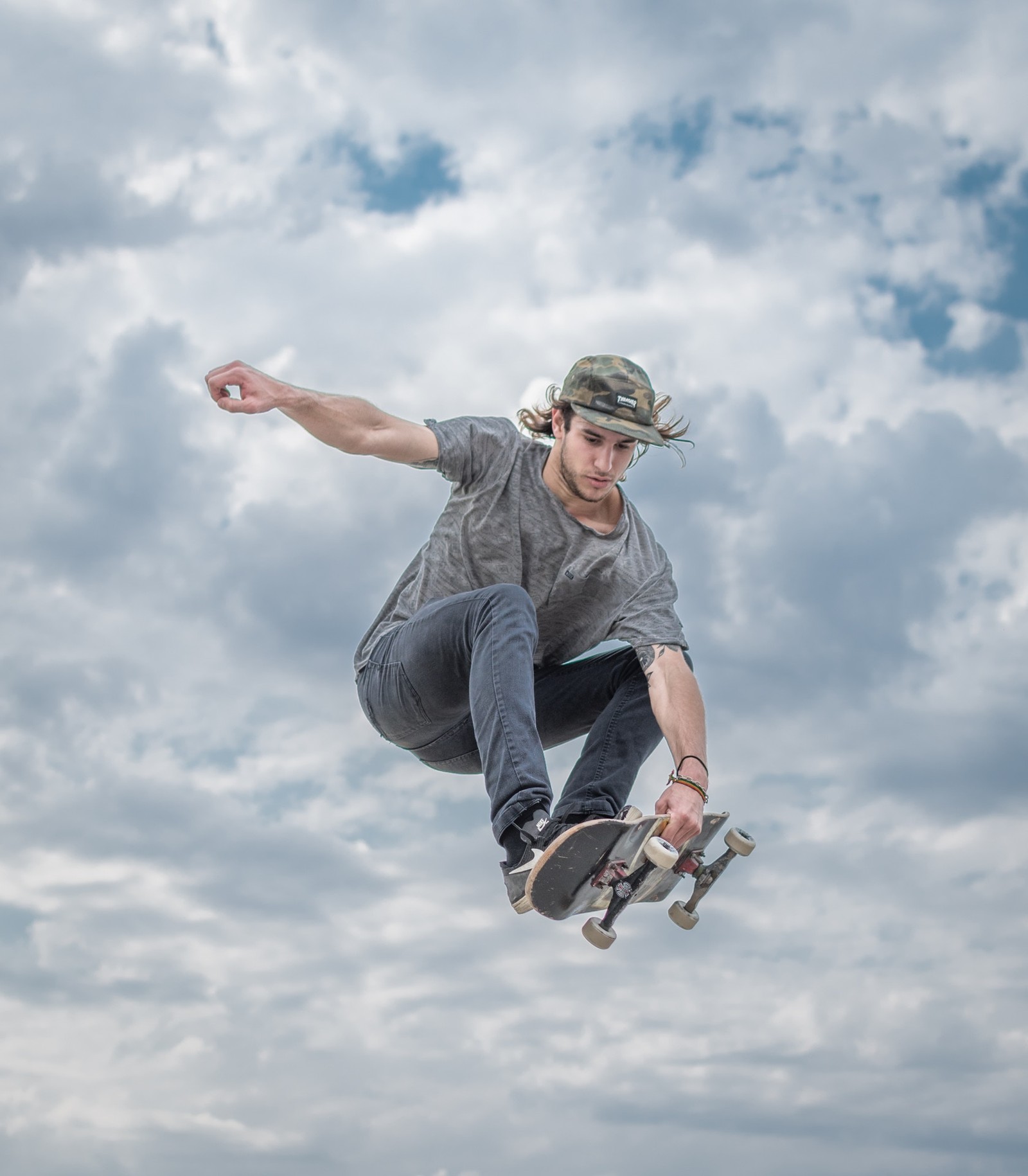 Arafed skateboarder in mid air doing a trick on a cloudy day (skateboarding, extreme sport, skateboard, recreation, snowboarding)