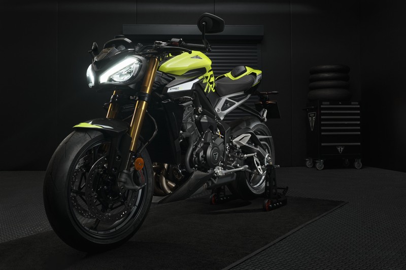 Крупный план мотоцикла, припаркованного в гараже с черным полом (triumph street triple 765 moto2 edition, 2022, тёмный фон, черный темный, велосипеды)