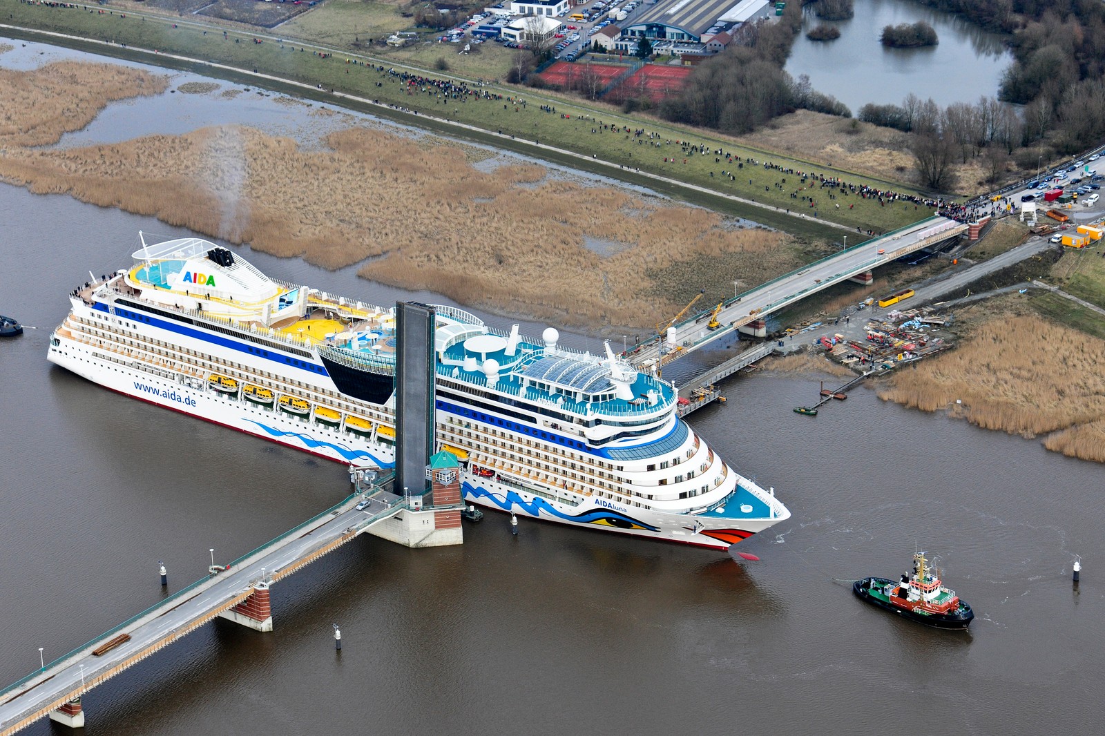 Ein angelegtes kreuzfahrtschiff in einem gewässer mit einer brücke (kreuzfahrtschiff, schiff, wassertransport, wasserstraße, transport)