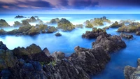 Serene Seascape at Dusk with Rocky Shoreline and Tranquil Waters