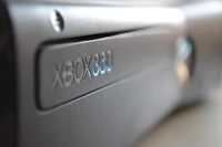 Close-up de um console Xbox 360 mostrando seu design preto elegante e logotipo.