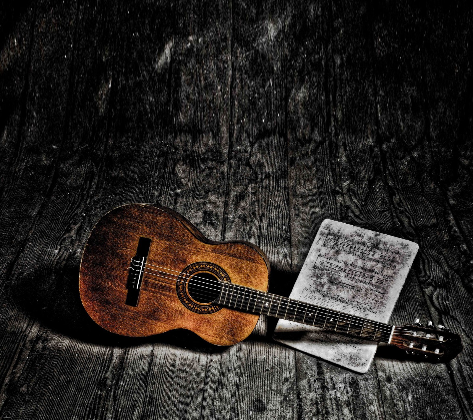 A close up of a guitar and a sheet of music on a wooden floor (acoustic, classical, dark, guitar, music)