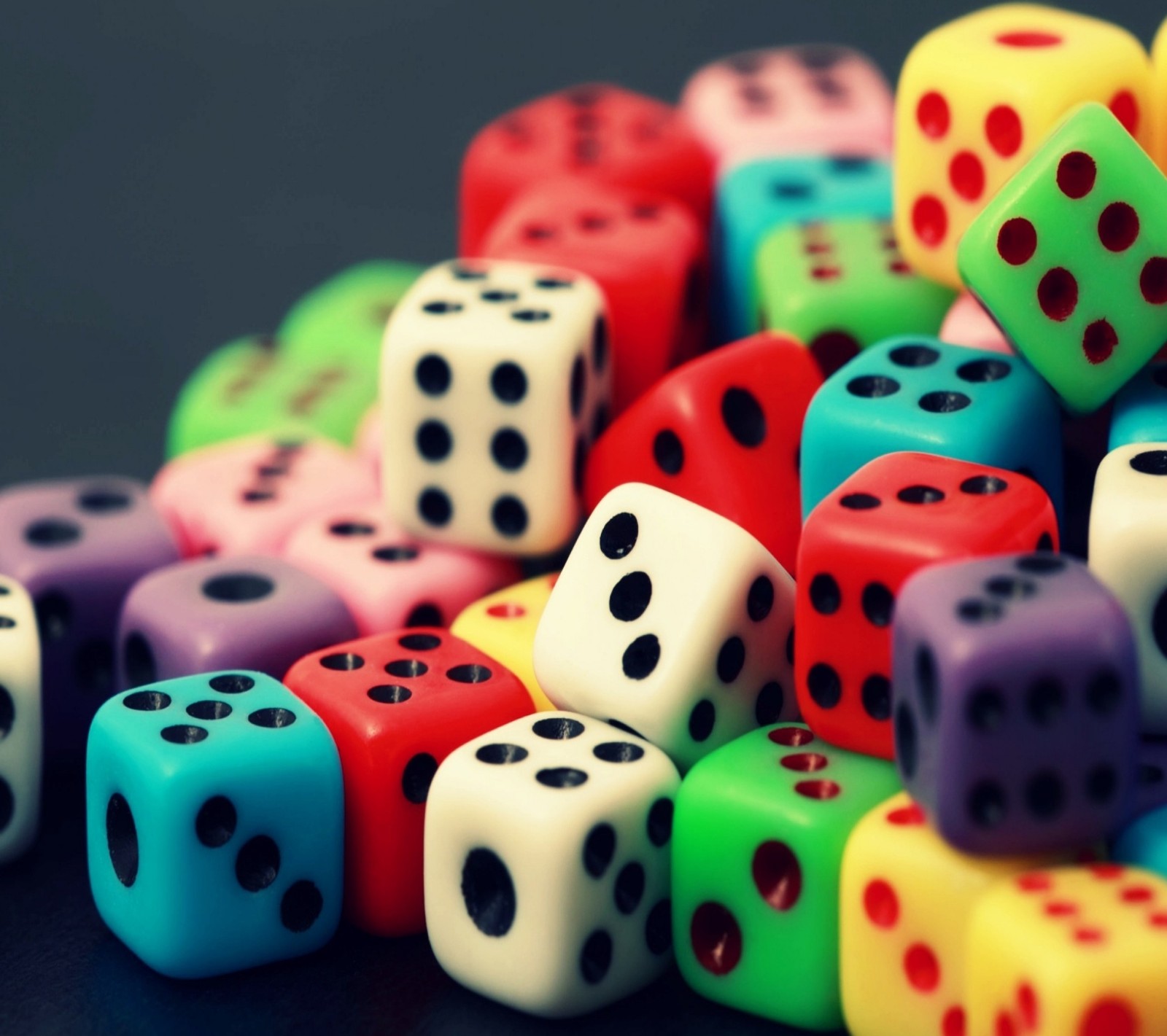 A close up of a pile of dice sitting on top of a table (colores, dados)