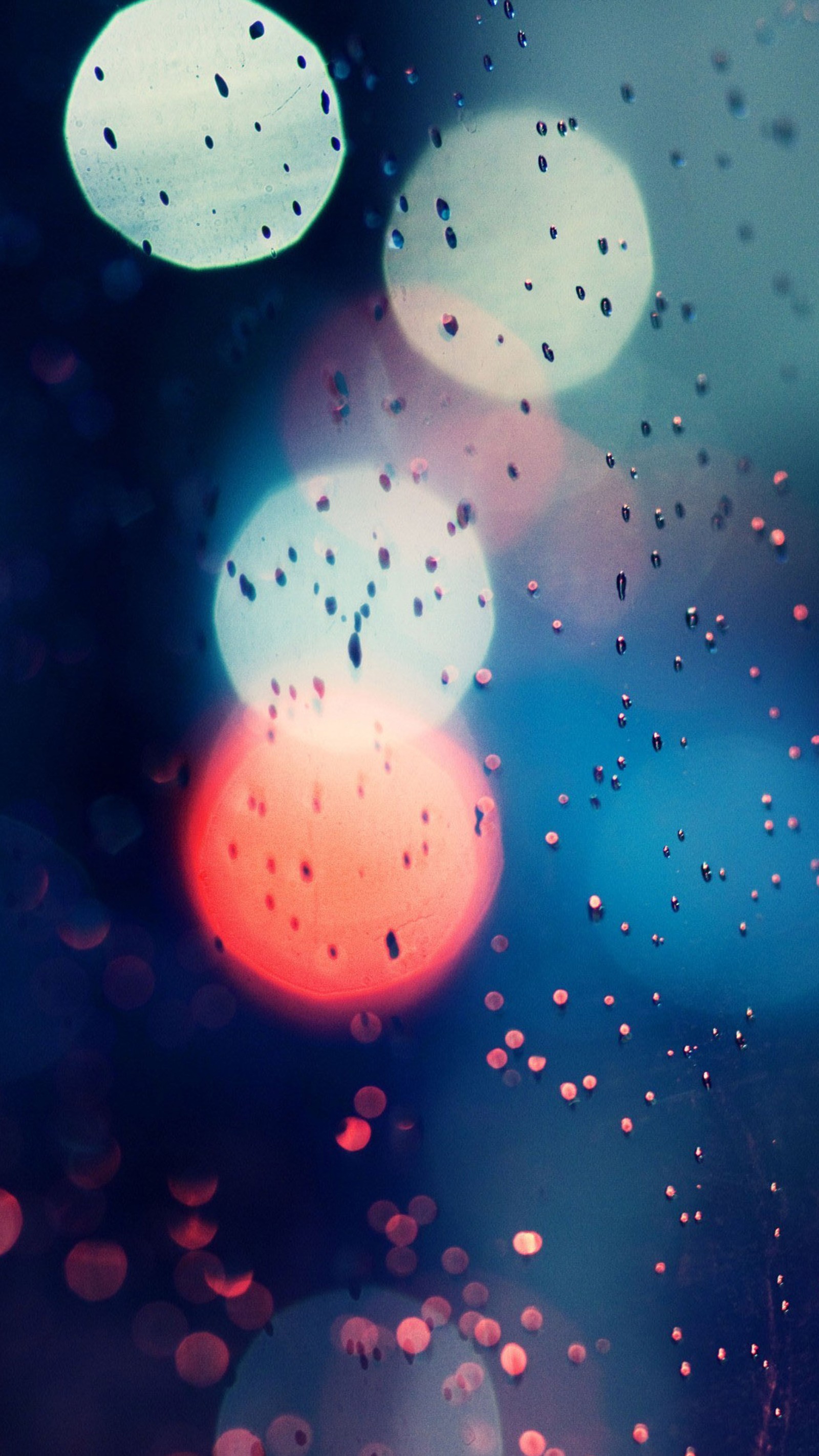 A close up of a rain covered window with a red and blue light (abstract, light drop)