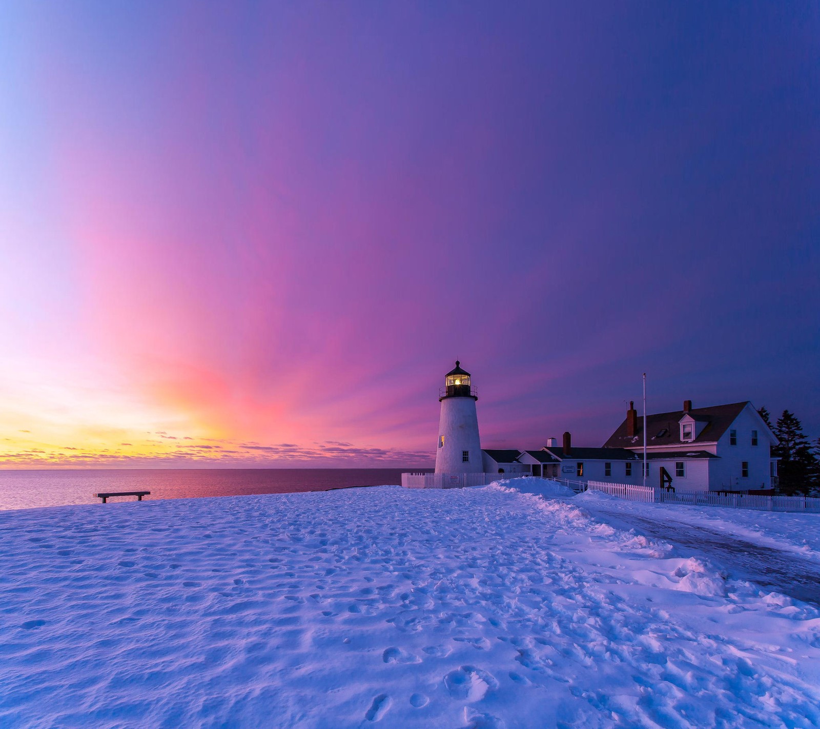 Vista aérea de um farol em uma praia nevada ao pôr do sol (farol, casa, luz, mar, céu)