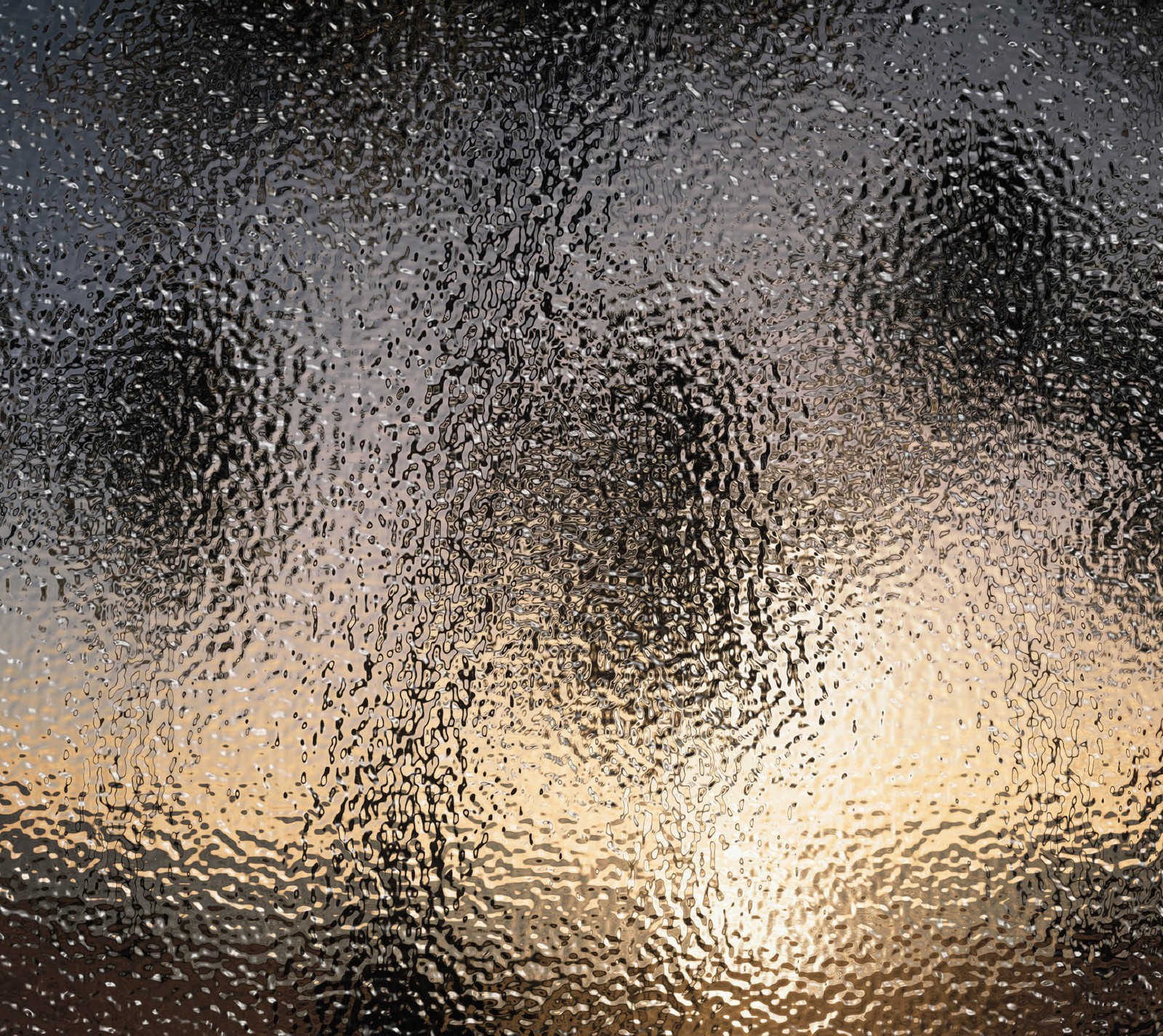 A close up of a window with a sunset in the background (abstract, black, brown, glass, rain)