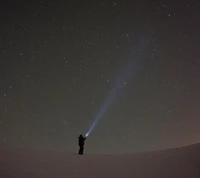 Figura en silueta iluminando el cielo nocturno con estrellas