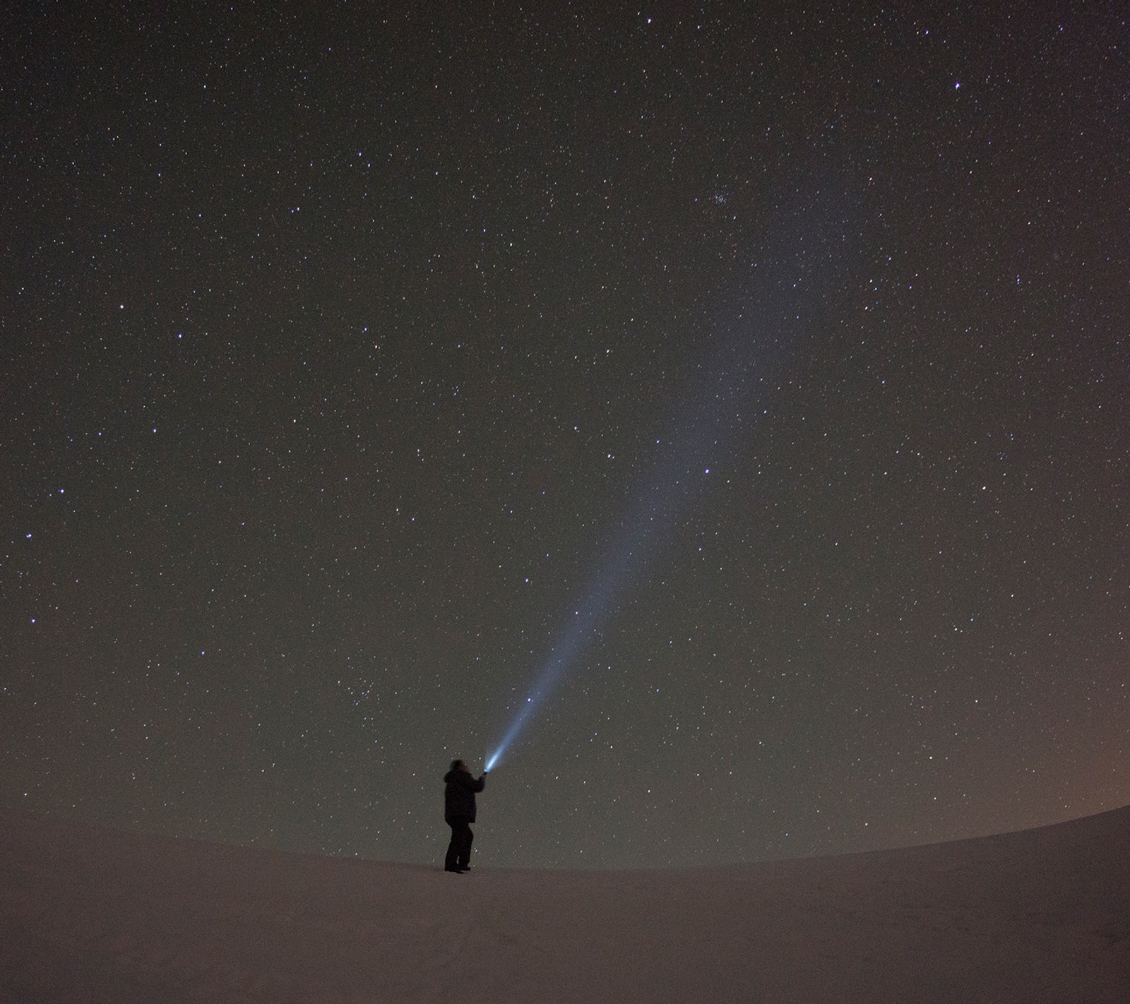 Une personne debout dans la neige avec une lampe de poche à la main (gece resimleri, uzun pozlama, photographie de yildiz, yildiz fotografi, yildiz resmi)